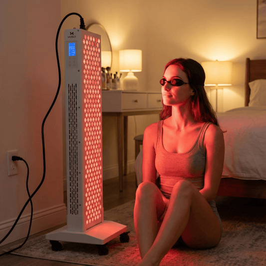 Red light therapy wetenschap: persoon gebruikt een roodlichttherapie paneel thuis met beschermbril