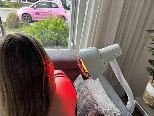 Vrouw gebruikt een infraroodlamp op haar schouder in een thuissituatie.